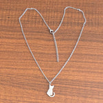 Silver-tone cat pendant necklace on a wooden surface