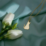 Close-up of a gold-tone cat pendant on a teal background