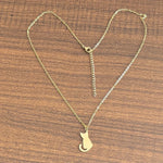 Gold-tone cat pendant necklace on a wooden surface