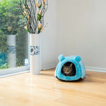 A tabby cat looks out from the Blue Armarkat tube bed beside a window