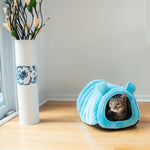 A cat rests in the Armarkat Blue velvet tube bed shown from the side