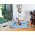 A tabby cat sits on the Blue Armarkat bolstered bed in a living room