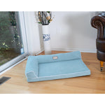 Blue Armarkat bolstered pet bed beside a window