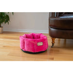 Armarkat Pink cuddle bed placed beside a chair on a wood floor