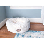 Plush Armarkat cuddler bed placed beside a window on a wood floor