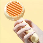Yellow cat grooming brush held in one hand